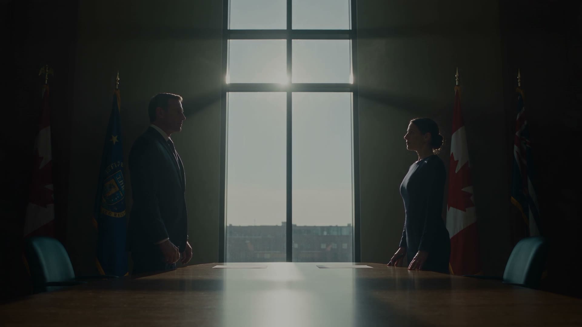 Two figures stand facing each other across a boardroom table, a bright window between them.